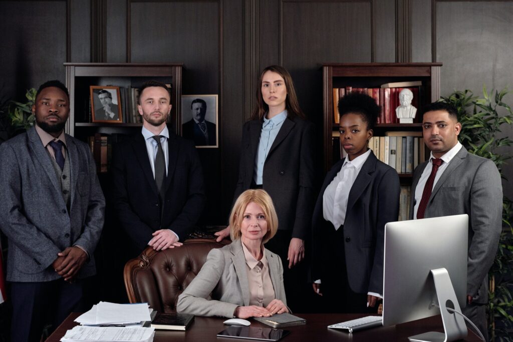 A group of people in business suits in a wood-panelled office, with one person seated at a desk